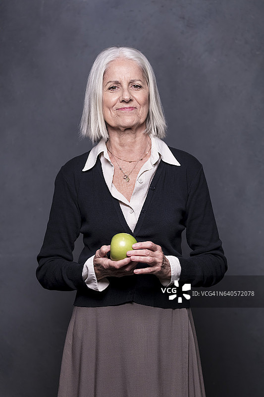 一个老妇人拿着青苹果的肖像图片素材