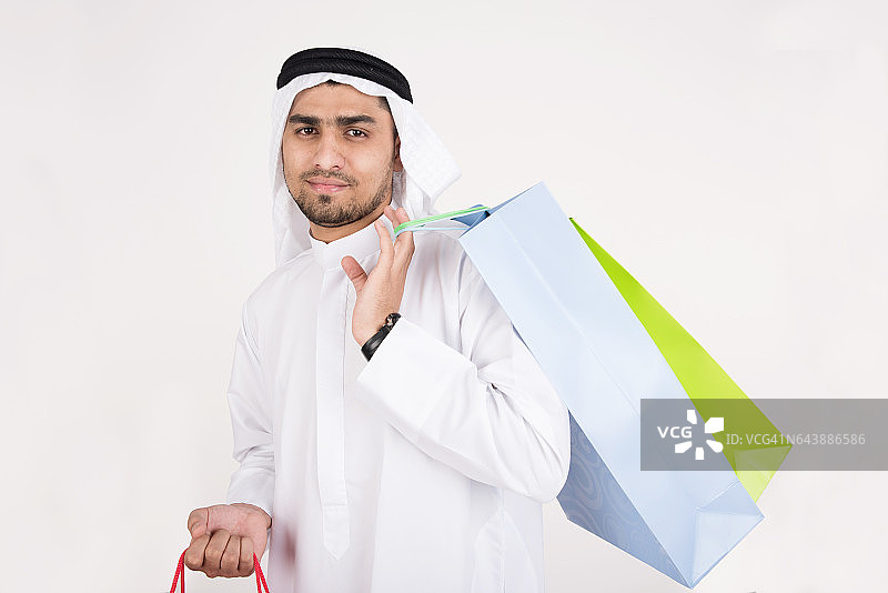阿拉伯穆斯林男子穿着传统服装，拿着购物袋图片素材