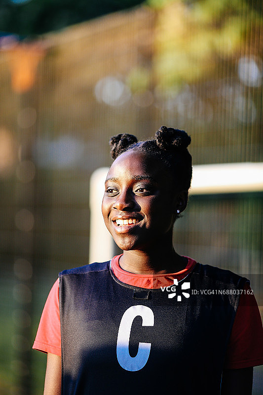年轻女子的肖像微笑和穿着网球围嘴在户外，城市体育球场图片素材