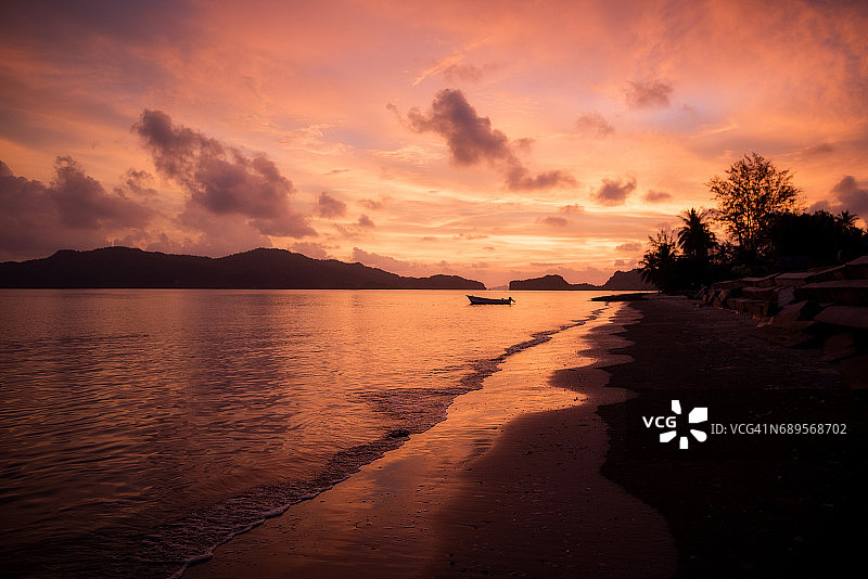 在空旷的热带海滩上，日落时绚丽的黄昏天空图片素材