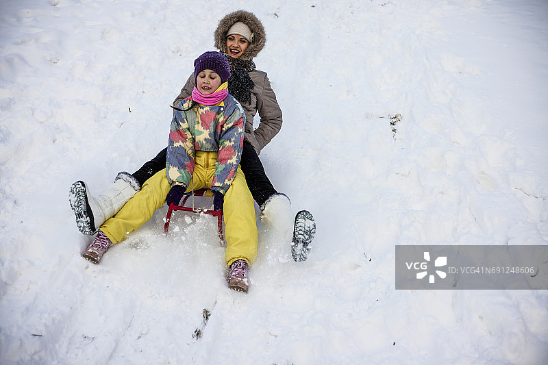 母亲和女儿喜欢坐雪橇图片素材