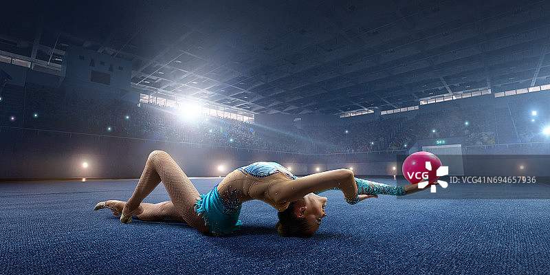 体操女运动员在大型专业舞台上用体操球进行表演图片素材