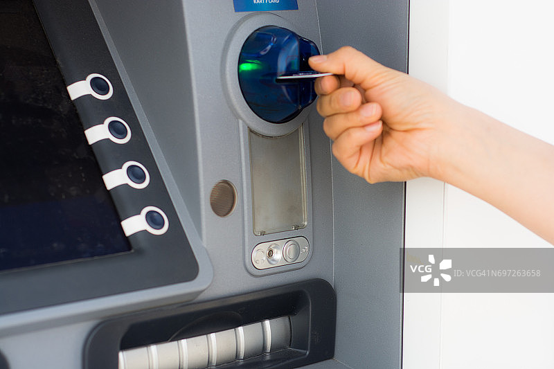 用手将信用卡插入银行ATM机图片素材