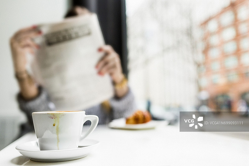 一名女子在咖啡店边吃早餐边看报纸图片素材