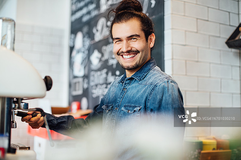 微笑的咖啡师在咖啡馆操作咖啡机图片素材