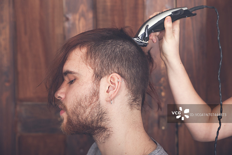 一个年轻人正在用他的女朋友用理发机理发图片素材