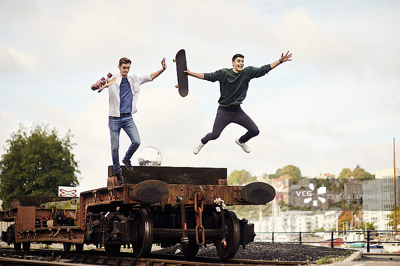 英国布里斯托尔，两个年轻人从火车轨道上的拖车上跳下图片素材