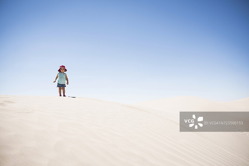 美国犹他州的小撒哈拉沙漠，一个蹒跚学步的小女孩站在沙丘顶上图片素材