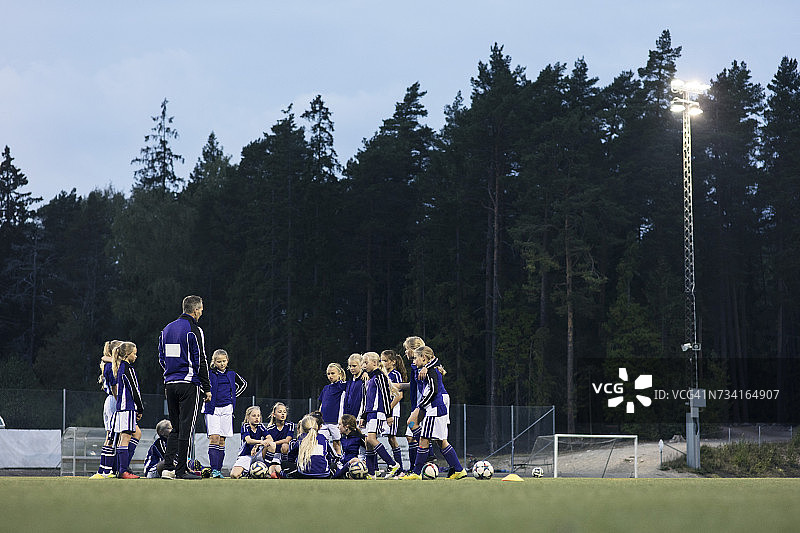 教练和女足队员在球场上靠着树站着图片素材