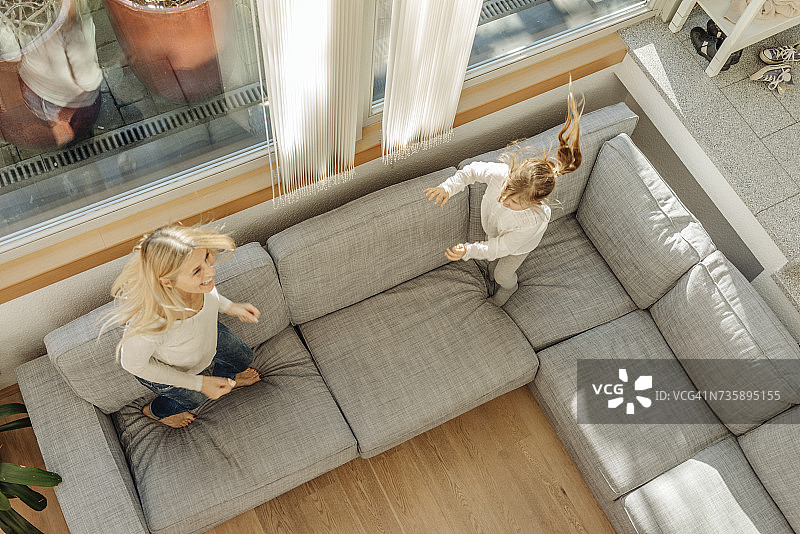 成熟的女人和女孩在家里的沙发上蹦蹦跳跳图片素材