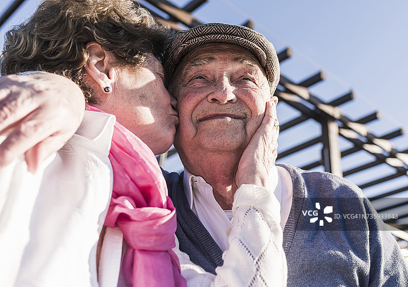 一个被妻子亲吻的快乐老人的肖像图片素材