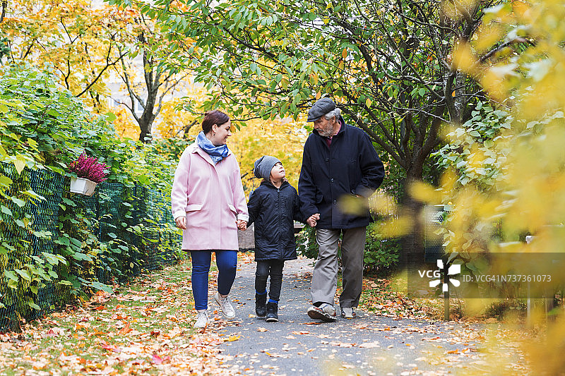秋天，全身的男孩和曾祖父和母亲在公园散步图片素材