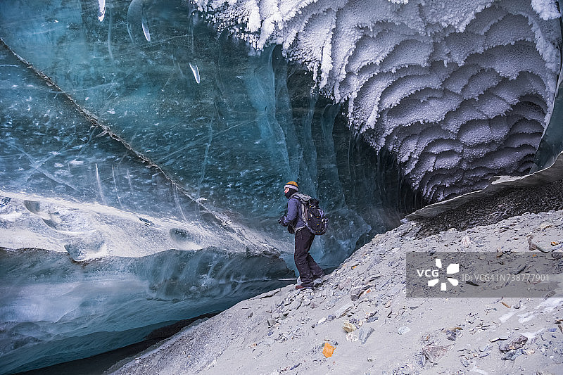 一名男子在阿拉斯加山脉坎威尔冰川的冰下探索隧道图片素材