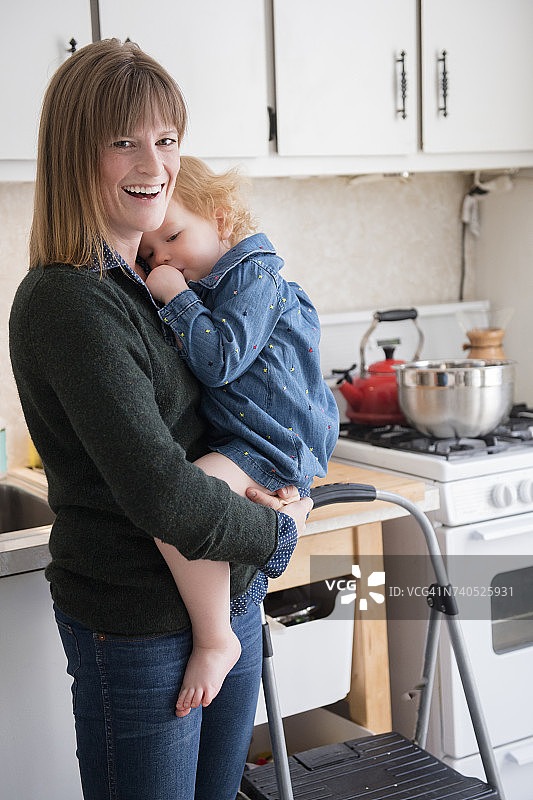 白人母亲抱着女儿在厨房吮拇指图片素材