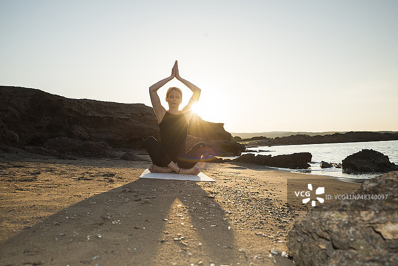 希腊，克里特岛，日落时分，一个女人在海滩上练习瑜伽图片素材