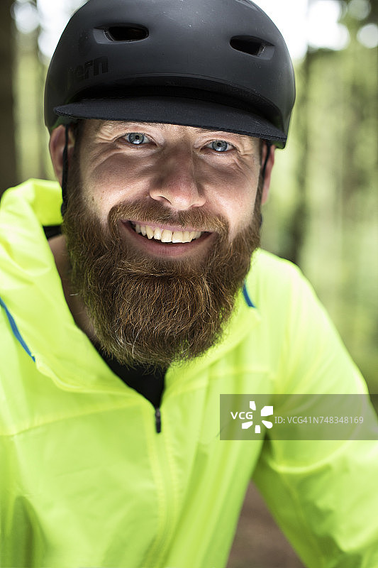 戴着黑色自行车头盔的满脸胡须的微笑男子的肖像图片素材