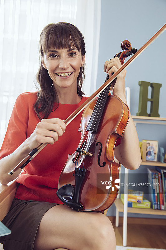 一个拿着小提琴的女人在孩子的房间里的肖像图片素材