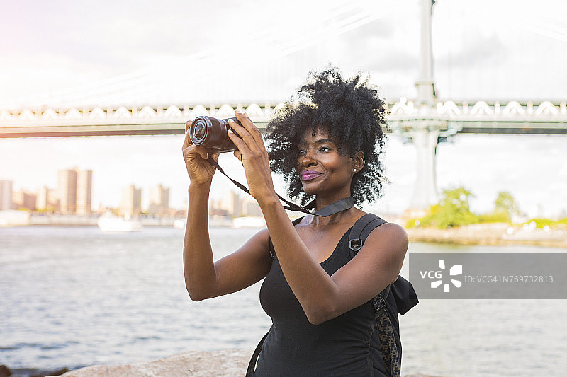 美国，纽约，布鲁克林，女人看着摄像机在水边图片素材