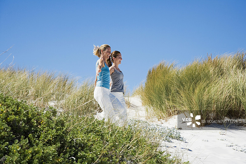 母亲和女儿手牵手在沙滩上奔跑图片素材