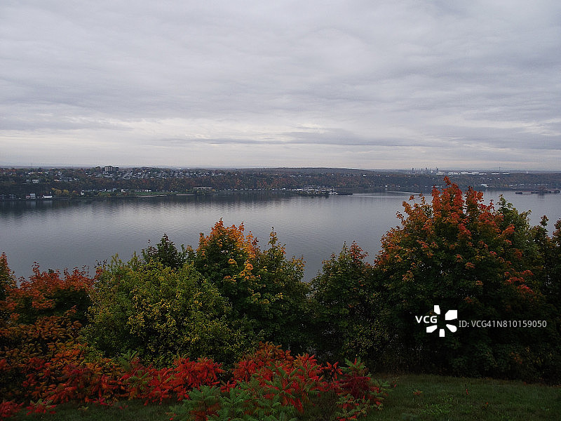 魁北克市附近的河流，秋天的树木覆盖着五颜六色的树叶图片素材