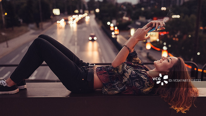 放松的女孩在桥上发短信和抽烟图片素材