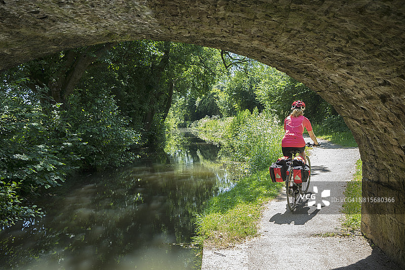 女性自行车旅游探索运河边小径在夏天图片素材