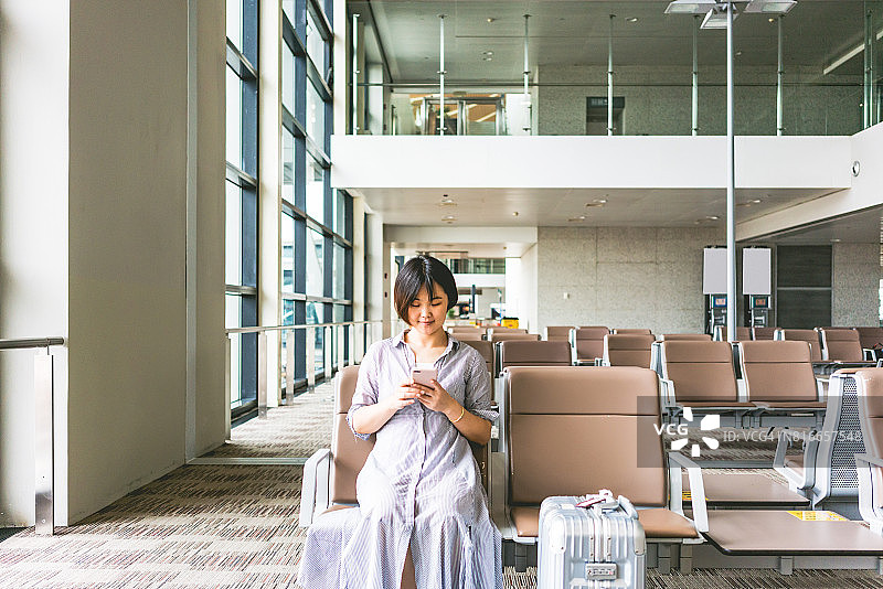 在机场等待航班时看智能手机的女性图片素材