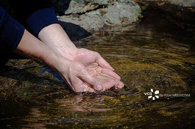 美丽的手在狂野的小溪上。干净的水流入人们的手中。图片素材