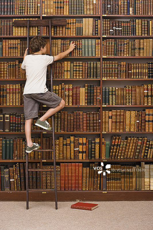 男孩在图书馆爬梯子图片素材