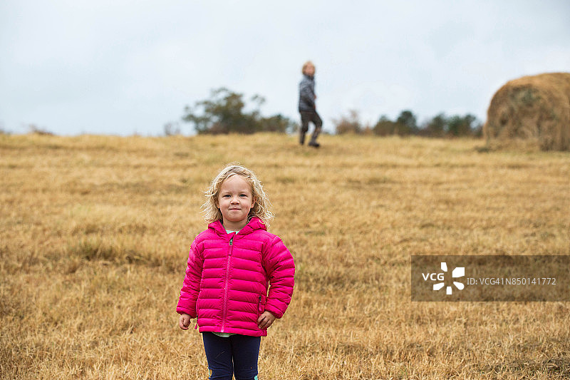 穿着粉红色夹克的微笑小女孩在草地上图片素材