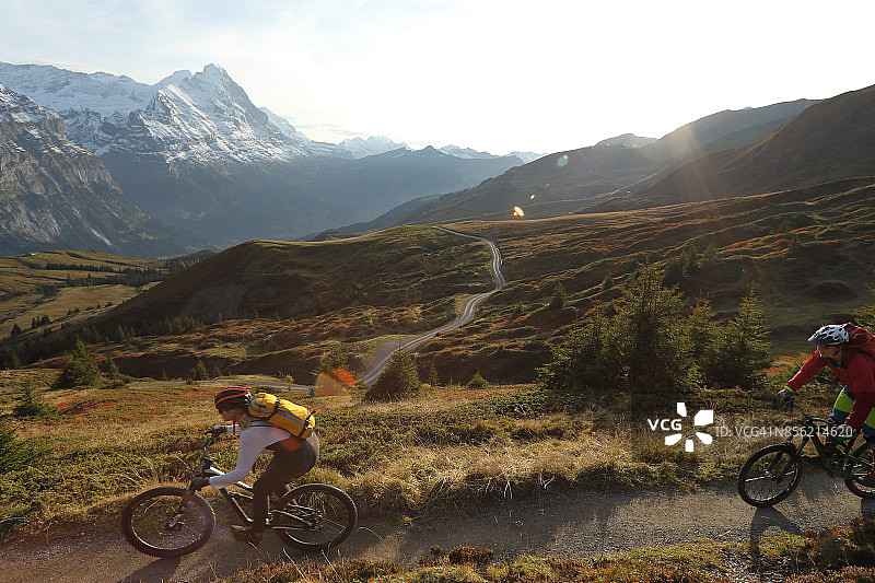 山地自行车手沿着小路穿过高山草甸和山脉图片素材