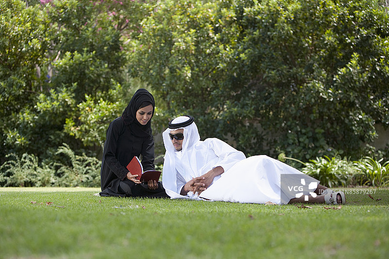 阿拉伯夫妇在公园看书。图片素材