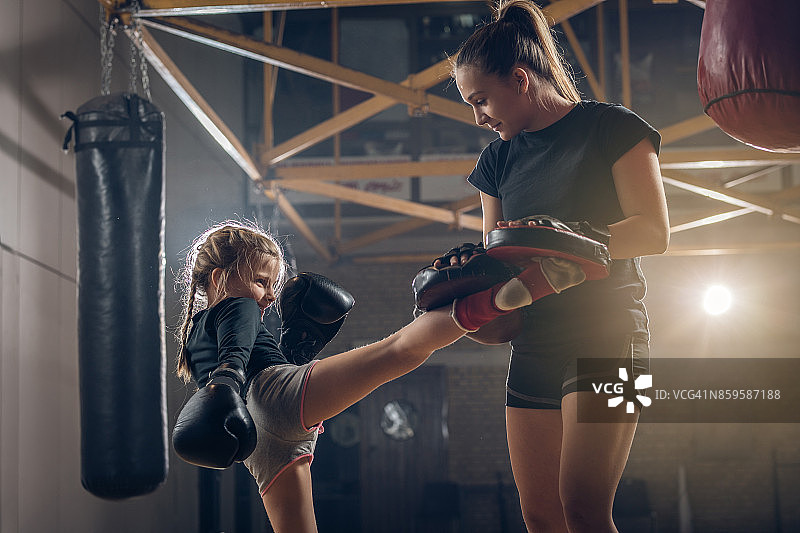 小女孩和女教练练习踢腿拳击。图片素材
