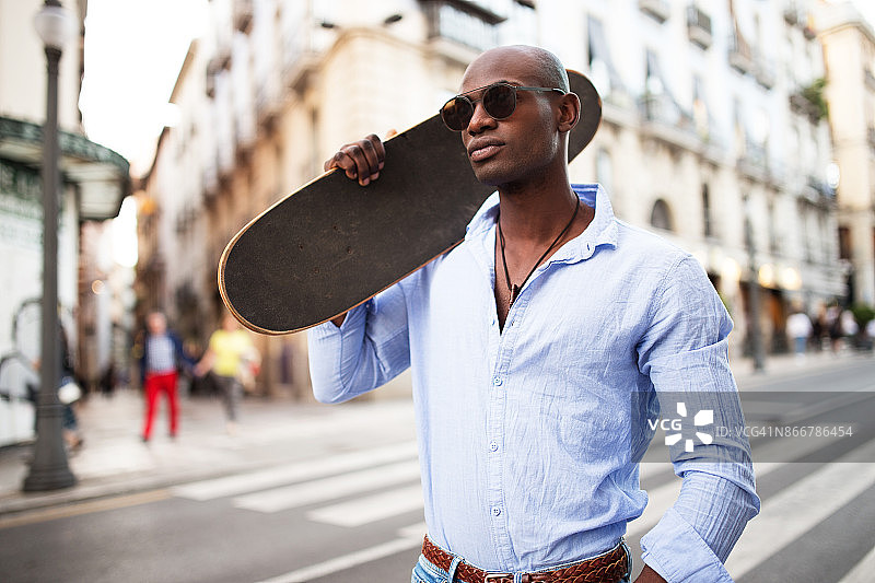 英俊的非洲男子与滑板。图片素材