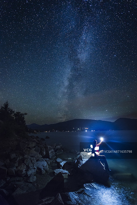 在加拿大不列颠哥伦比亚省的奥卡那根湖畔，一个人在黑暗中把灯笼举过头顶图片素材