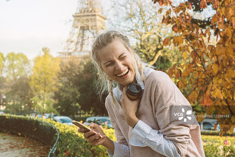 金发女孩在看手机上的搞笑信息，巴黎图片素材