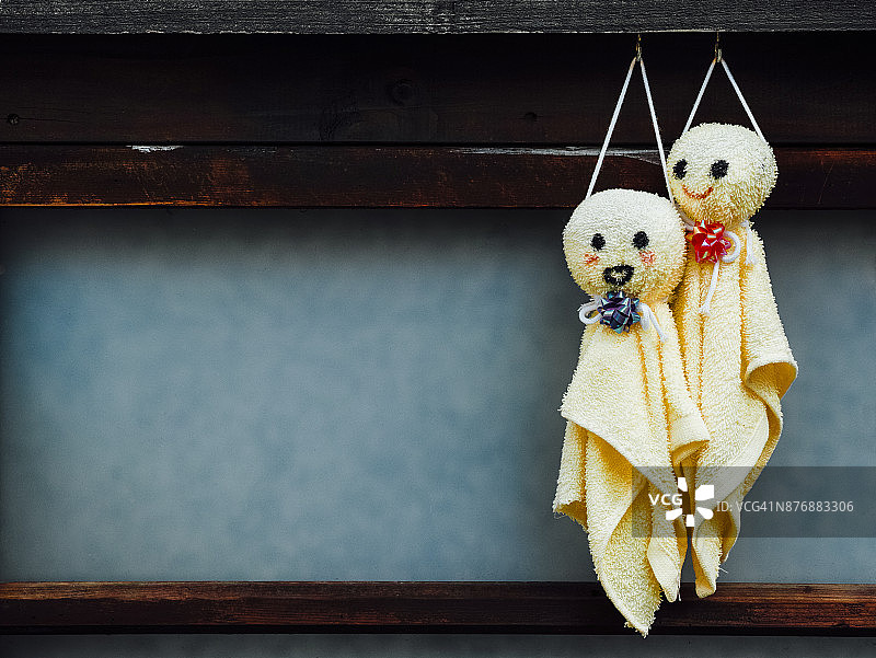Teru Teru bozu布娃娃用黄色的手巾挂在窗户上图片素材