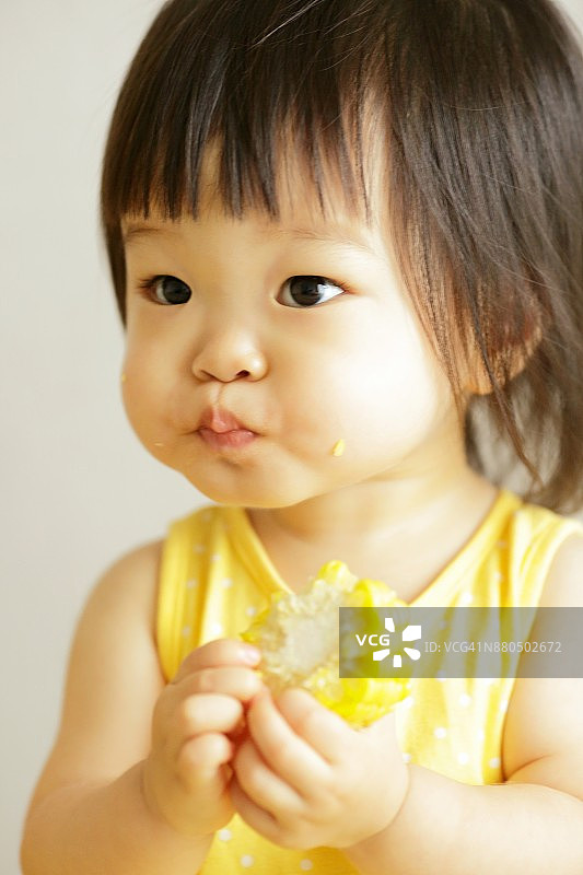 小女孩吃着甜玉米，满嘴都是图片素材