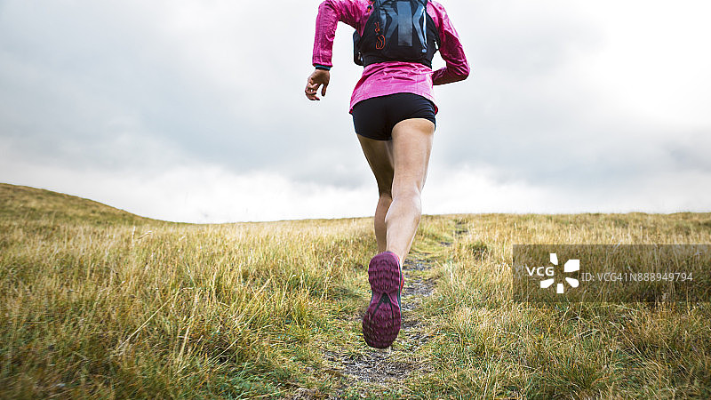 女运动员跑上长满草的山坡图片素材