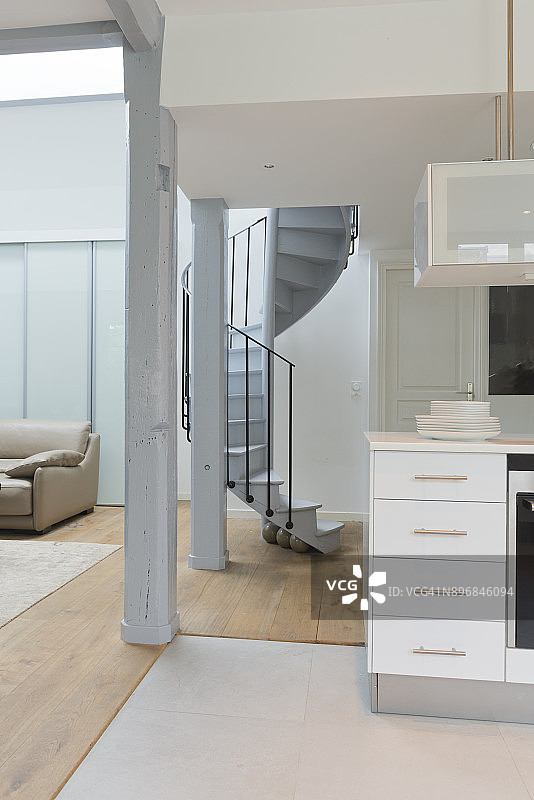 宽角度的生活空间和厨房与螺旋楼梯。图片素材