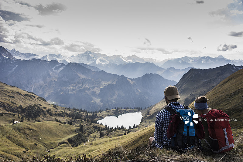 德国，巴伐利亚，奥伯斯特多夫，两个徒步旅行者坐在阿尔卑斯山的风景图片素材