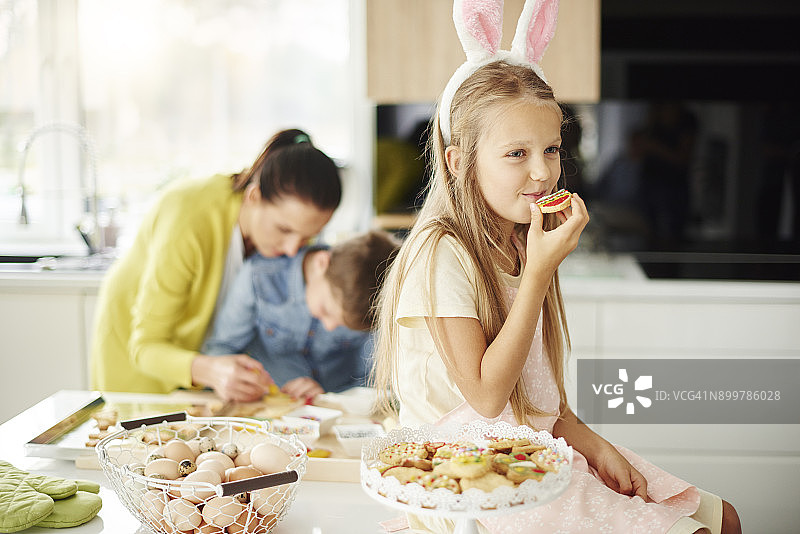 女孩在厨房柜台上吃复活节饼干图片素材