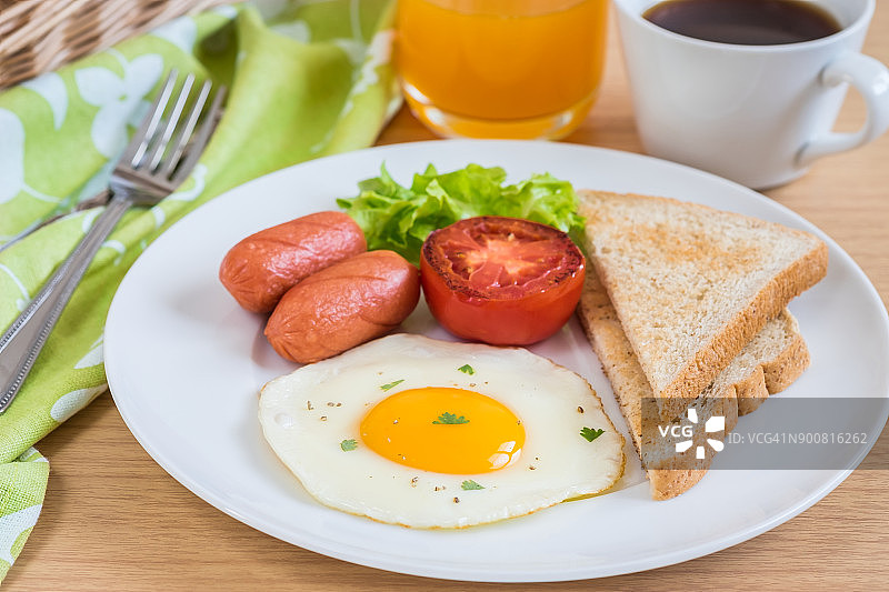 早餐有煎蛋、吐司、香肠、蔬菜、咖啡和橙汁图片素材