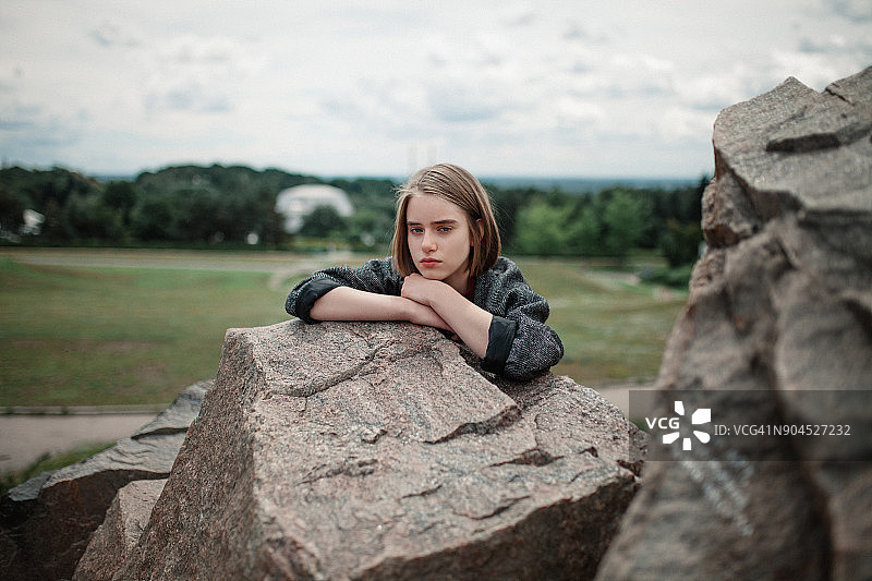 年轻女子靠在岩石上休息图片素材