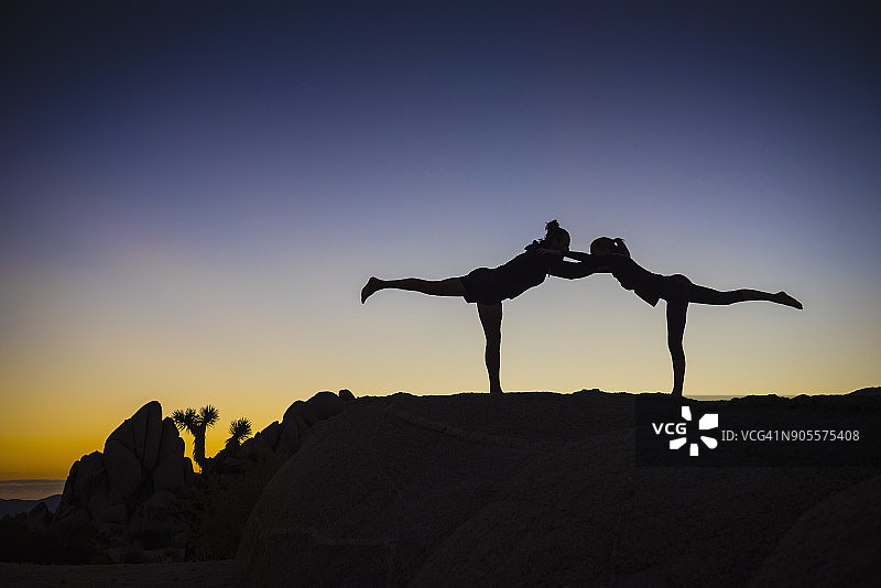 西语裔夫妇的剪影伸展双腿在沙漠日落图片素材