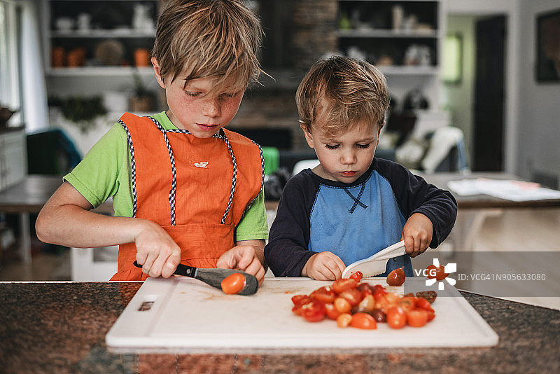 两个男孩在厨房切西红柿图片素材