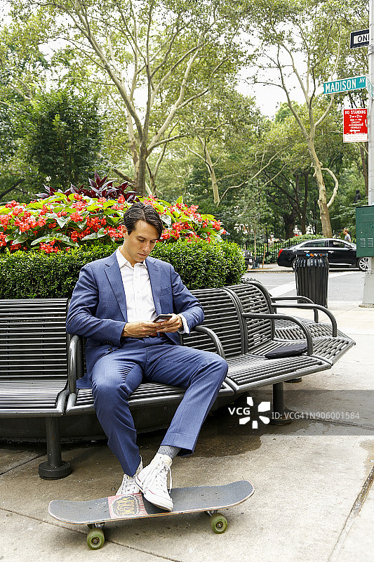 一个白人商人在公园长椅上用手机发短信图片素材