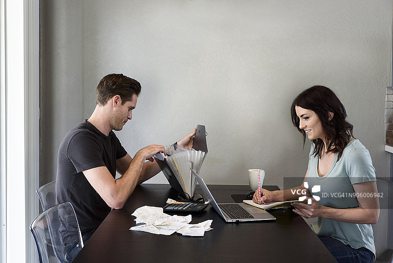 白人女人在笔记本电脑旁边写笔记而男人在搜索文件图片素材