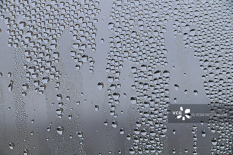 春雨滴在雾蒙蒙的窗户上。图片素材