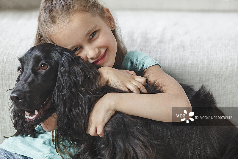 微笑的女孩在家里拥抱小狗的肖像图片素材